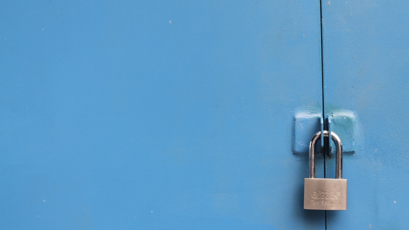 A padlock on a gate — verification that actually blocks something, rather than a badge that decorates it