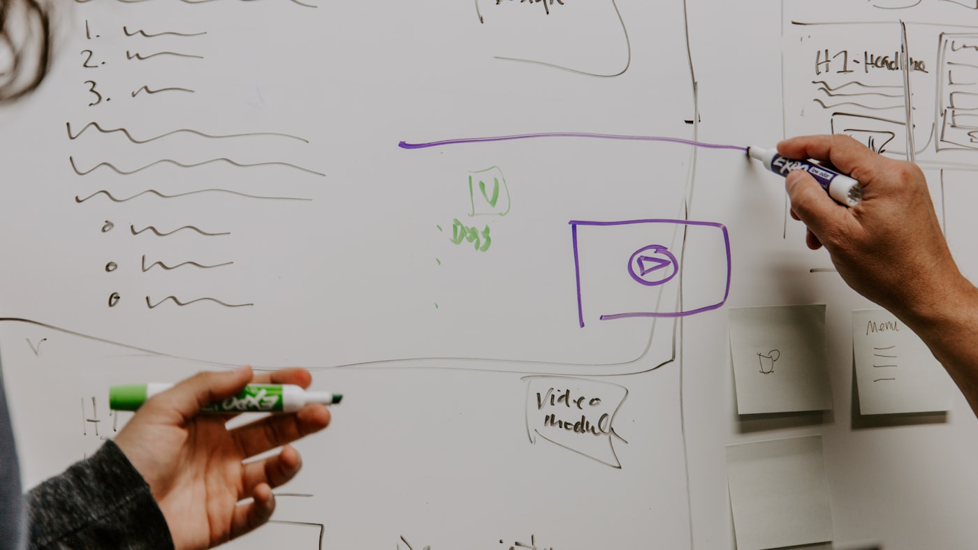 Two people working through a problem at a whiteboard