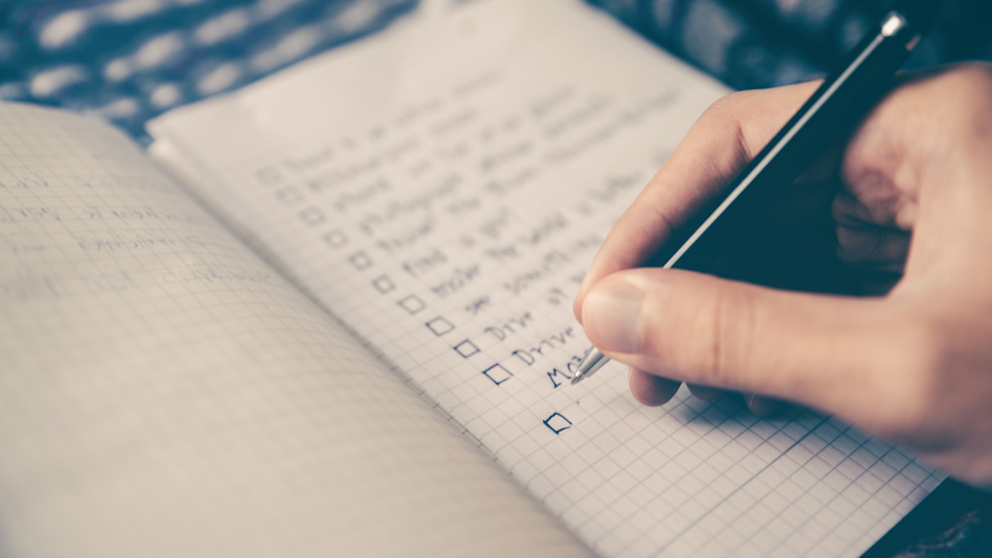 A handwritten list on a notebook — deciding what stays and what gets crossed off
